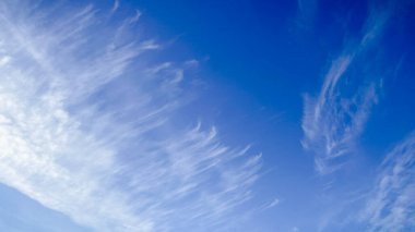 Açık bir kış gününde açık mavi gökyüzünde parlak güneş, narin beyaz sirrus bulutlarının arasından parlıyor..