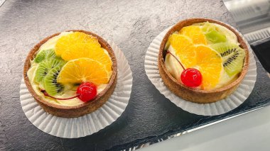 Taze kivi dilimleri, portakal ve vişneli kremalı iki gurme meyveli tart..