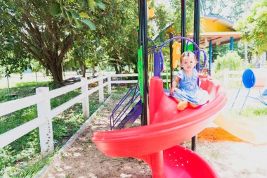 Sevimli küçük kız mutlu bir şekilde gülüyor oyun bahçesinde sarı güneş ışığı mutluluğunda,