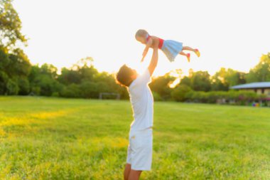 Gün batımında parkta oynayan sağlıklı bir baba ve kız. Mutlu, eğlenceli, gülümseyen, yaşam tarzı. Siluet.