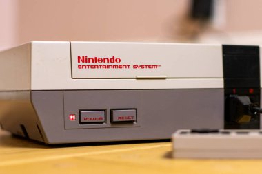 Bir Nintendo Eğlence Sistemi ve fişi takılı bir kontrol sistemi. NES popüler bir retro konsoldur.