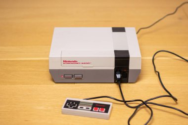 Bir Nintendo Eğlence Sistemi ve fişi takılı bir kontrol sistemi. NES popüler bir retro konsoldur.