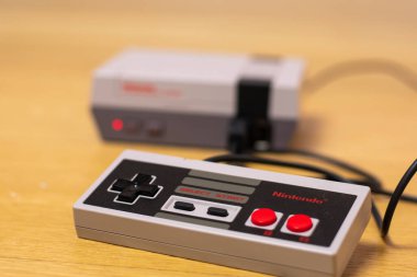 Nintendo Entertainment System Classic Edition Denetleyicisi, tahta bir zemin üzerinde konsola bağlı,.