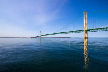 Mackinaw Köprüsü Panorama. Güneşli bir günde Mackinaw Köprüsü ufukta bir Büyük Göller yük gemisiyle Michigan Gölü 'nün berrak mavi sularına yansıdı..