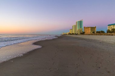 Myrtle Beach şehri şafak vakti Atlantik Okyanusu 'nun geniş kumlu sahilinde ufuk çizgisi..