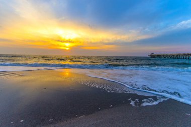 Sunrise over an Atlantic Ocean beach with wooden fishing pier in downtown Myrtle Beach, South Carolina.