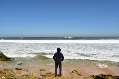 Yogyakarta, Endonezya. 10 Temmuz 2019. Kapüşonlu bir adamın sahilde durduğu fotoğraf.