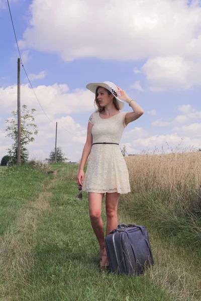 Женщина с чемоданом на краю поля — стоковое фото