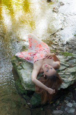 Güzel genç kadın bir kayaya yalan