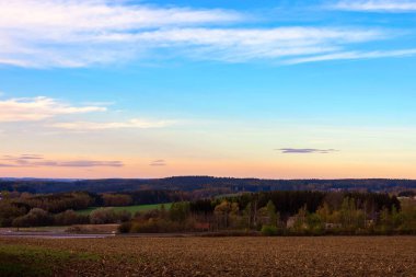 Gökyüzünde bulutlar olan bir tarlanın üzerinde sonbahar günbatımı