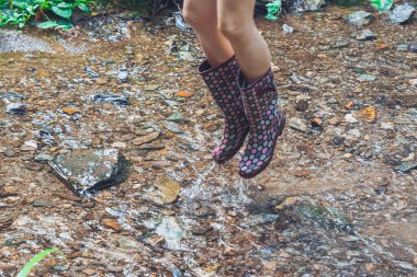 Kadın kauçuk çizmelerle havaya atlıyor.