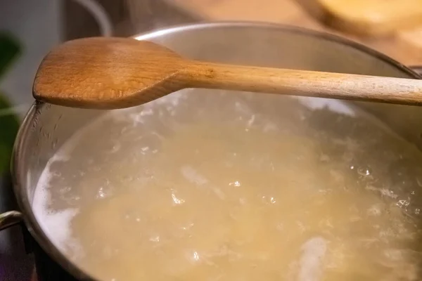 Cooking pot with water and wooden spoon — Stock Photo, Image