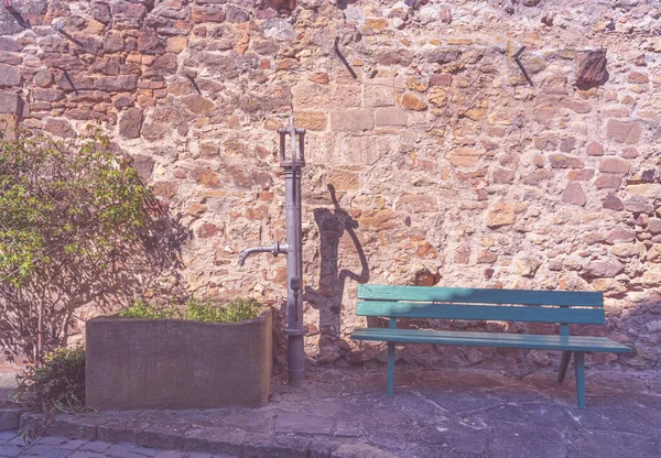 벤치가 있는 돌벽 앞에 있는 오래 된 수도관 — 스톡 사진
