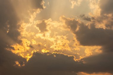 Şiddetli, fırtınalı bir gün batımı, alttaki gri fırtına bulutlarının üzerinde parlayan parlak bulutlar. Güneş ışınları ya da güneş ışınları içinden fışkırıyor.