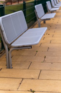 Sade gri banklar sakin bir parkta sıcak, altın bir patika boyunca uzanıyor. Huzurlu ortamın tadını çıkarmak için ideal bir ortam. Yoldan geçen insanları sessiz sakin düşünmeye ve eğlenmeye davet ediyorlar..