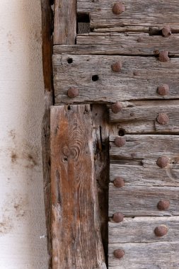 Eski bir köyde, yıpranmış ahşap bir kapı dimdik ayakta duruyor, kırsal çekiciliğini sergiliyor. Paslı çivilerle süslenmiş kapı, zaman ve tarihle ilgili hikayeler anlatıyor, merak uyandırıyor..