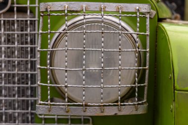 Kırsal yeşil bir kamyonda tel ızgarayla korunan klasik bir far bulunur. Resimli bir kırsal kesimde duruyor. Nostalji ve açık yollarda seyahat anılarını çağrıştırıyor..