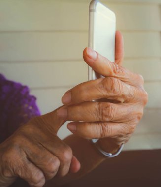 Yaşlı bir kadın bir cep telefonu tutan eller