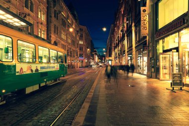 Helsinki, Finlandiya - 5 Ekim 2019: Finlandiya 'nın başkenti Helsinki' nin şehir merkezindeki alışveriş merkezinden geçen yeşil tramvaya odaklanın.