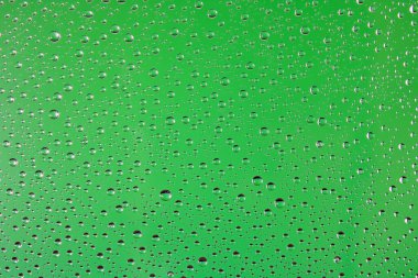 Açık yeşil arka planda cam üzerindeki su damlaları. Soyut