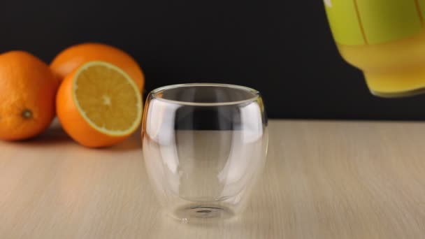 ガラス瓶からオレンジジュースをグラスに入れる 新鮮なオレンジジュースのガラスを閉じます 天然成分から健康的な朝食を準備します 自家製フルーツジューステーブルの上 オーガニックビタミンドリンク — ストック動画
