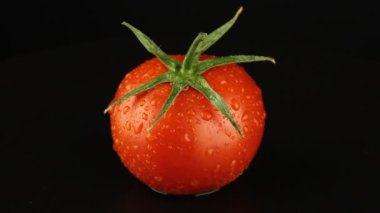 Taze domates siyah arka planda döner. Sağlıklı gıda konsepti.