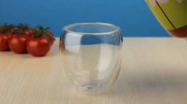 Camdan cam sürahiye domates suyu dökülüyor. Bir bardak taze domates suyu yakın plan. Masada ev yapımı meyve suyu var. Organik vitamin içeceği..