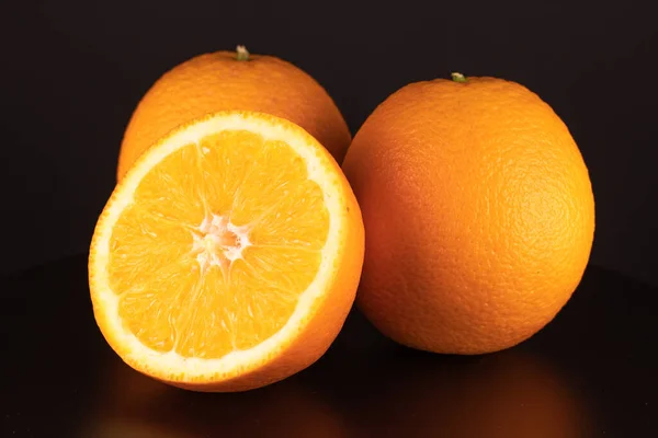 Eén Helft Twee Hele Sinaasappels Een Zwarte Achtergrond Close — Stockfoto