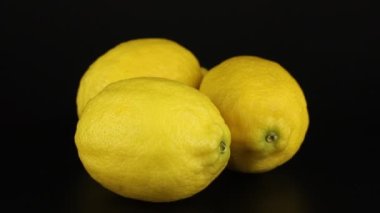 Three lemons rotates on a black background. Close-up video vitamin.