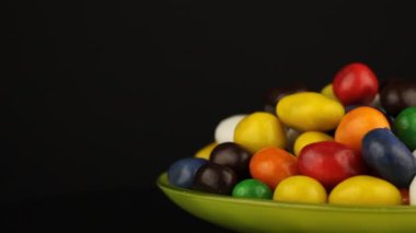 Siyah arkaplanda dönen renkli çikolatalı fıstıklar.