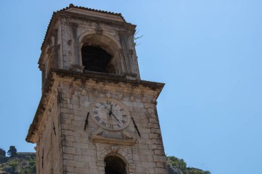 Bir dağ manzarası ve yeşil ağaçların arkasında görünen kilise kuleleri. Kotor Montenegro 'daki dağların arkasındaki eski ortaçağ kilisesi
