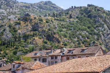 Dağlardaki eski Kotor Montenegro kasabası ve mavi gökyüzü arka planı. Yazın aydınlık ve güzel bir manzara açık bir günde.