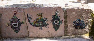 Taşın üstünde güzel bir balık. Çizimin deniz teması. Duvardaki süs. Sanat nesnesi.