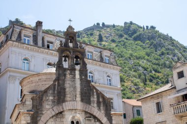 Eski binanın pencereleri ve mavi gökyüzü olan ön cephesinde üç antik çan olan ortaçağ kilisesi..