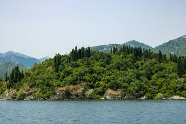 Açık bir gökyüzünün arka planına karşı göllü ve yeşil dağlı manzara. En büyük gölün panoramik manzarası. Harika bir yaz günü.