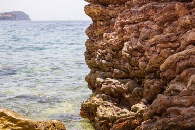 Denizin arka planında büyük bir taş var. Büyük taşlar grubu. Kayalar güzel suyun üzerinde duruyor. Kayalık sahil kıyısı.