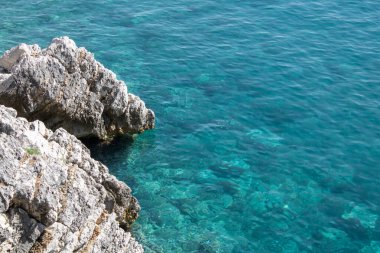 Büyük gri taşlardan oluşan bir grup. Kayalar güzel suyun üzerinde duruyor. Kayalık sahil kıyısı. Duvar kağıdı - deniz ve kayalar buluştu.