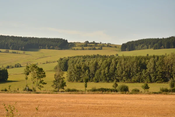 Field under the hills under a blue sky — Stock Photo, Image