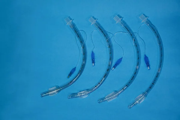 Tıbbi aletler. Farklı boyutlarda endotrakeal tüpler, mavi arka planda yakın plan çekimleri.