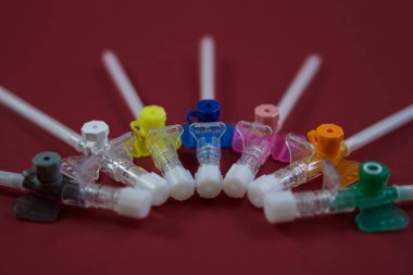 Kırmızı arka planda damar içi sondalar var. Yakın plan çekilmiş. çok renkli kateterlerin çapı farklıdır - en küçükten en büyüğe