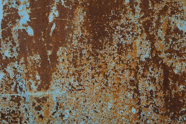 the texture of an old iron wall that was painted with blue paint. over time, the paint peeled off and the iron began to rust. from this beautiful stains went over the paint.