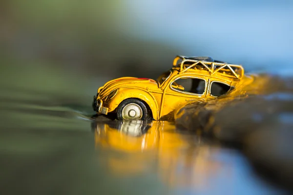 Small yellow toy car in ocean - Travel concept background