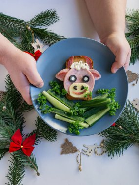 2021 'in yenilebilir boğa sembollü komik sandviçi. Ekmek, jambon, peynir ve zeytinden yapılmış. Çocuklar için Kahvaltı Fikri. Yılbaşı yemeği, bayram, Noel, yemek sanatı. Dikey.