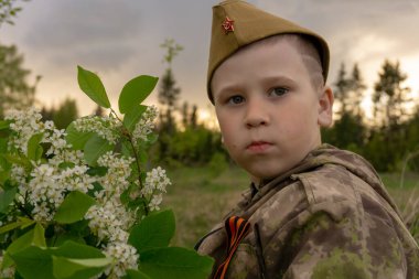Askeri üniformalı bir buket çiçekle bir çocuk. Zafer Günü.