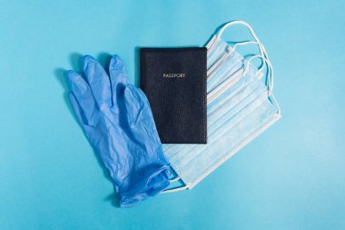 Salgından sonra seyahat et. Koronovirüsten sonra iyi yolculuklar. Eldivenler, pasaport, mavi arka planda maskeler, üst manzara. Metin için alanı olan düz bir yüzeyde güvenli yolculuk kavramı.