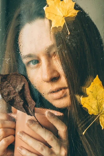 Smutná Dívka Kelímkem Mokrým Oknem Kapkami Deště Skle Žlutými Listy — Stock fotografie