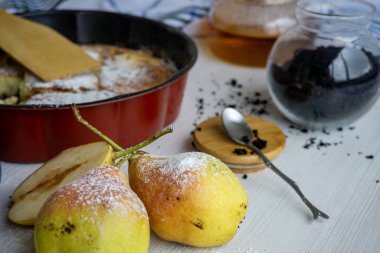 Ön planda armut olan beyaz bir masada ev yapımı armut turtası..