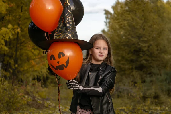 Chica divertida con un disfraz de bruja para Halloween con globos negros y naranjas. —  Fotos de Stock