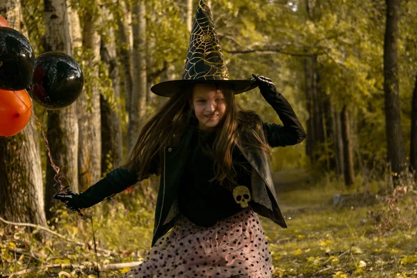 Chica divertida con un disfraz de bruja para Halloween con globos negros y naranjas. —  Fotos de Stock