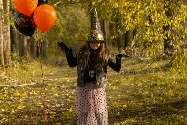 Chica divertida con un disfraz de bruja para Halloween con globos negros y naranjas. —  Fotos de Stock